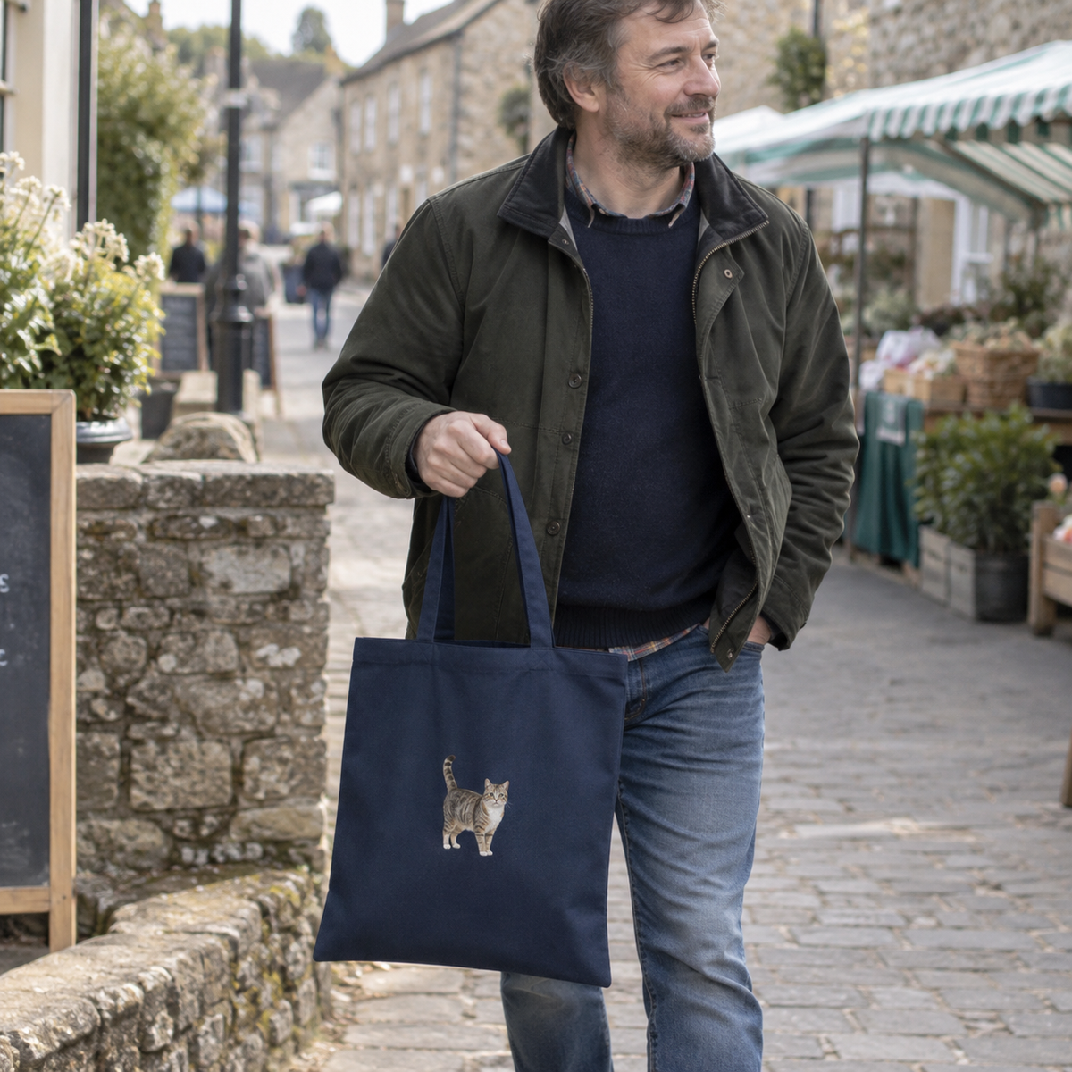 Man carrying a French navy personalised embroidered cat portrait tote bag on a village street