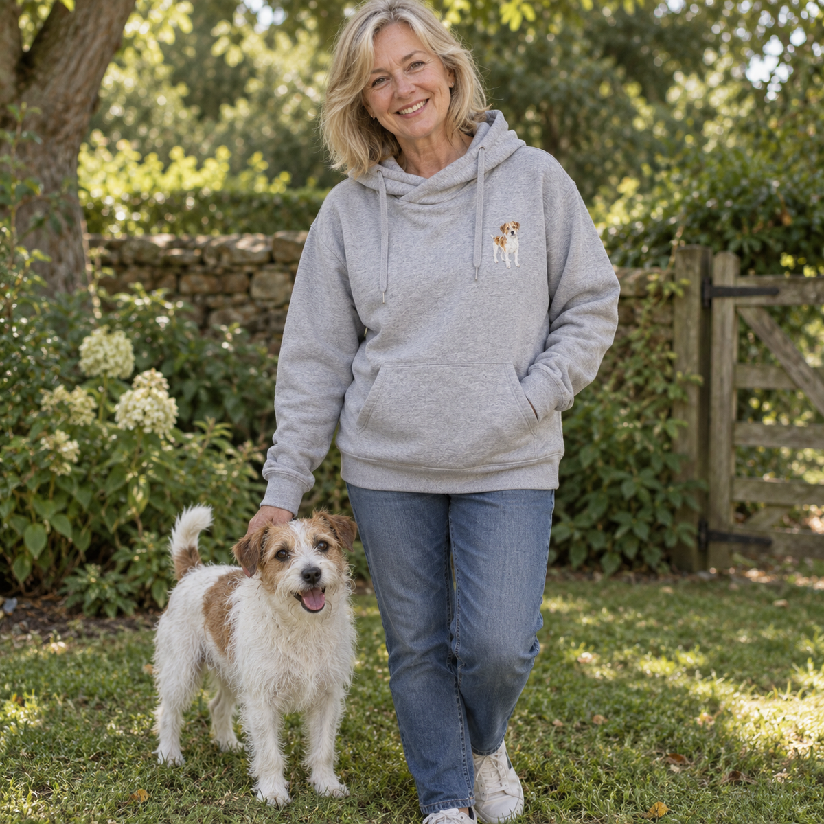 Woman wearing a personalised embroidered dog portrait cross neck hoodie with her terrier in a natural garden lifestyle photo