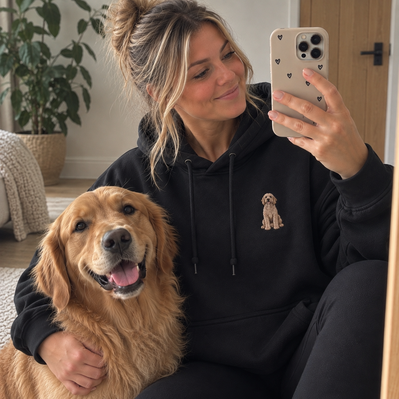 Woman wearing a jet black personalised embroidered pet portrait hoodie with a Golden Retriever in a natural UGC lifestyle photo