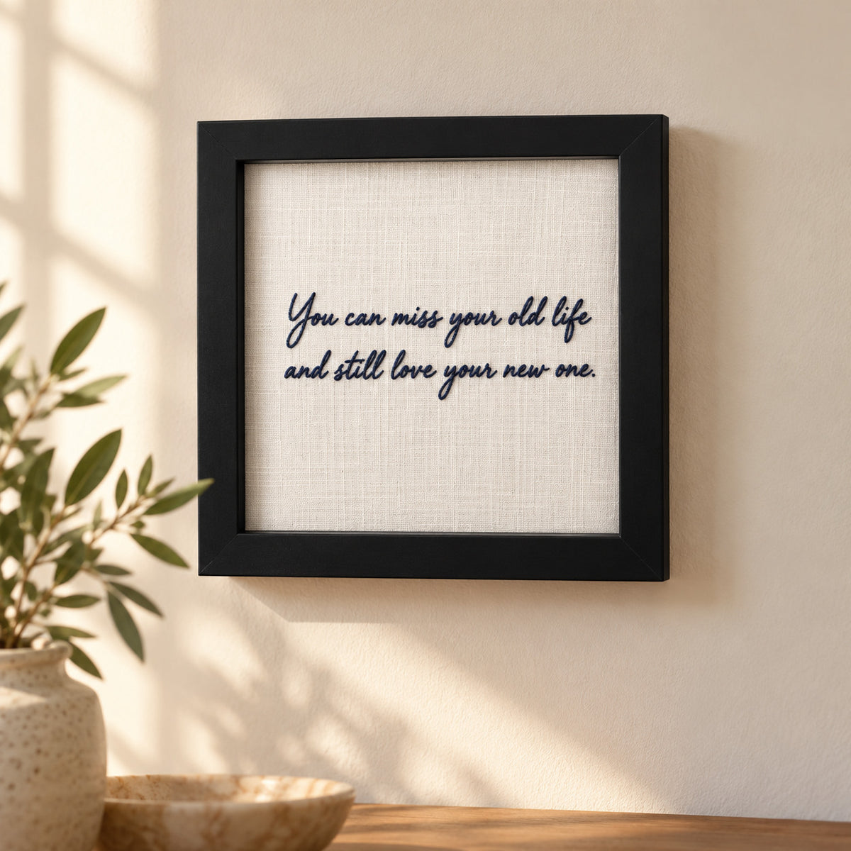Personalised embroidered message frame hanging on a wall with navy handwritten quote about life's new beginnings