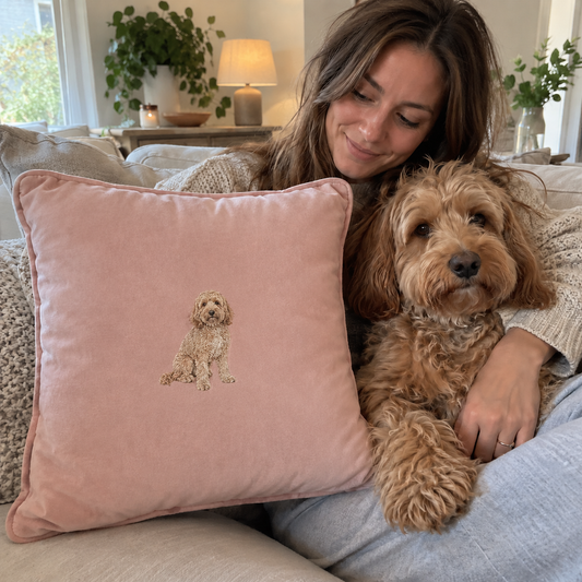 Woman with her dog beside a blush personalised embroidered pet portrait cushion with a small centred full-body dog design
