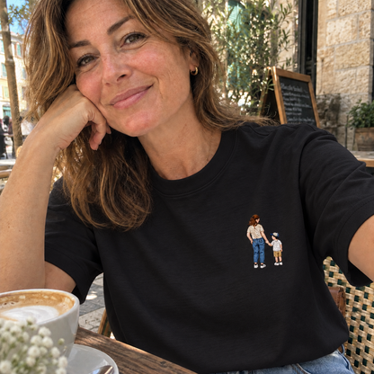 Woman wearing a black personalised embroidered T-shirt with a small full-colour mother and child portrait in a casual café setting